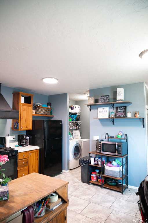 Kitchen featuring washer / clothes dryer, black appliances, premium range hood, and light tile floors
