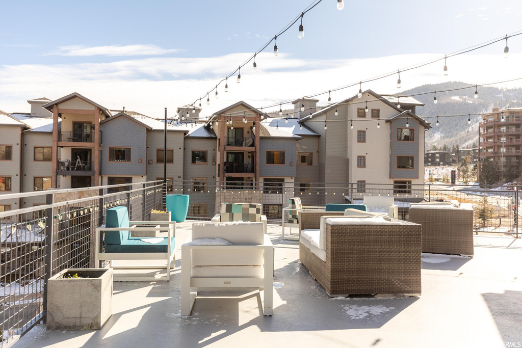 Snow covered patio featuring outdoor lounge area, a balcony, and a mountain view