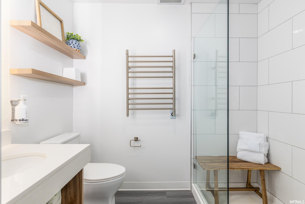Bathroom with vanity, hardwood / wood-style flooring, an enclosed shower, toilet, and radiator heating unit