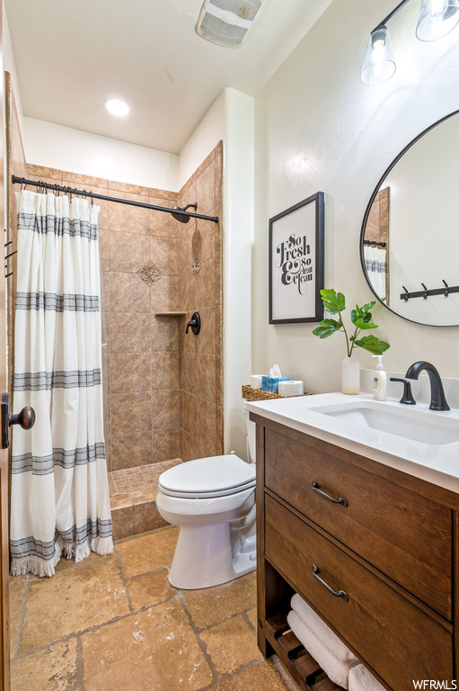 Bathroom featuring toilet, a shower with shower curtain, vanity with extensive cabinet space, and tile floors