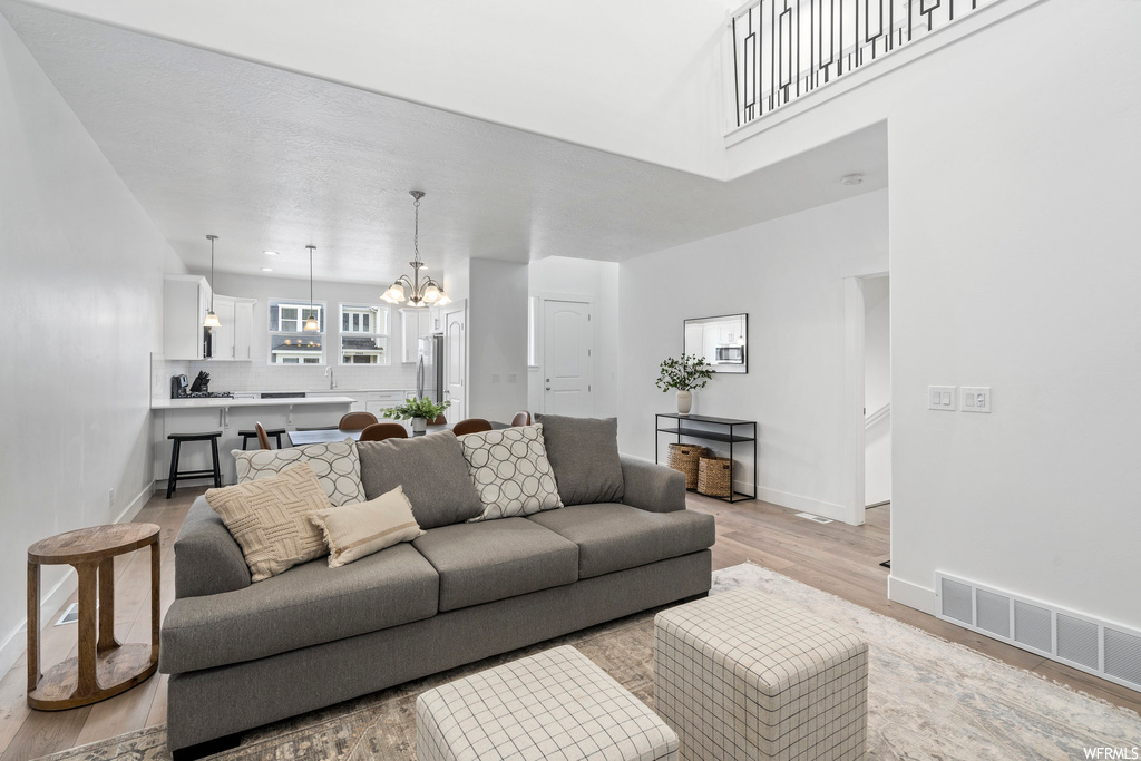 Living room with light hardwood / wood-style floors and a notable chandelier