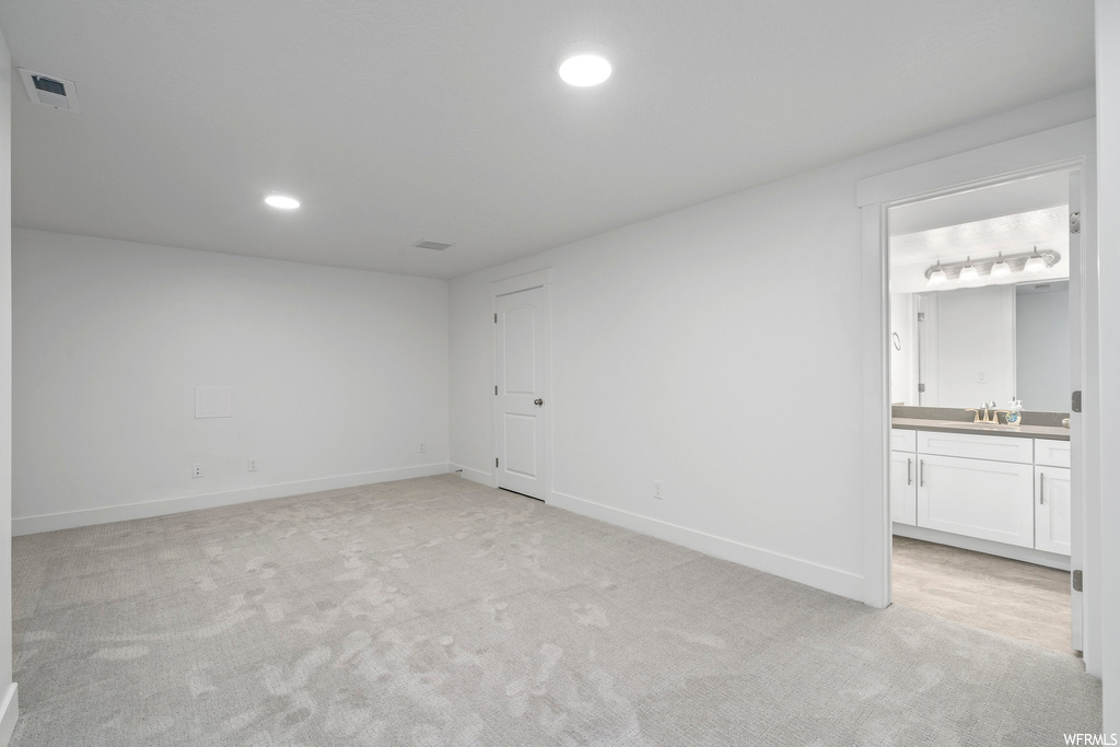 Unfurnished room with light colored carpet, track lighting, and sink
