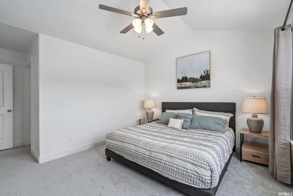 Bedroom featuring vaulted ceiling, ceiling fan, and light colored carpet