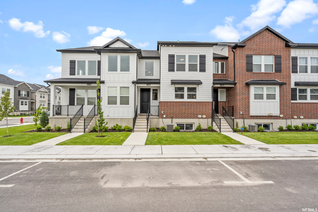 View of property with a front yard and central air condition unit