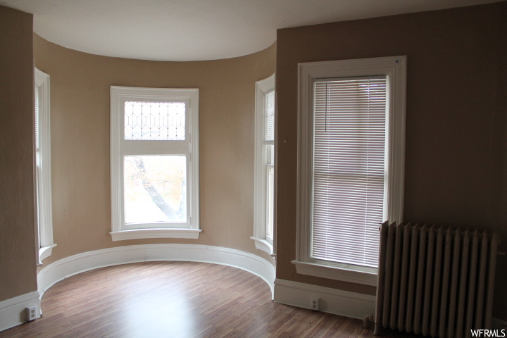 Spare room with hardwood / wood-style floors and radiator heating unit