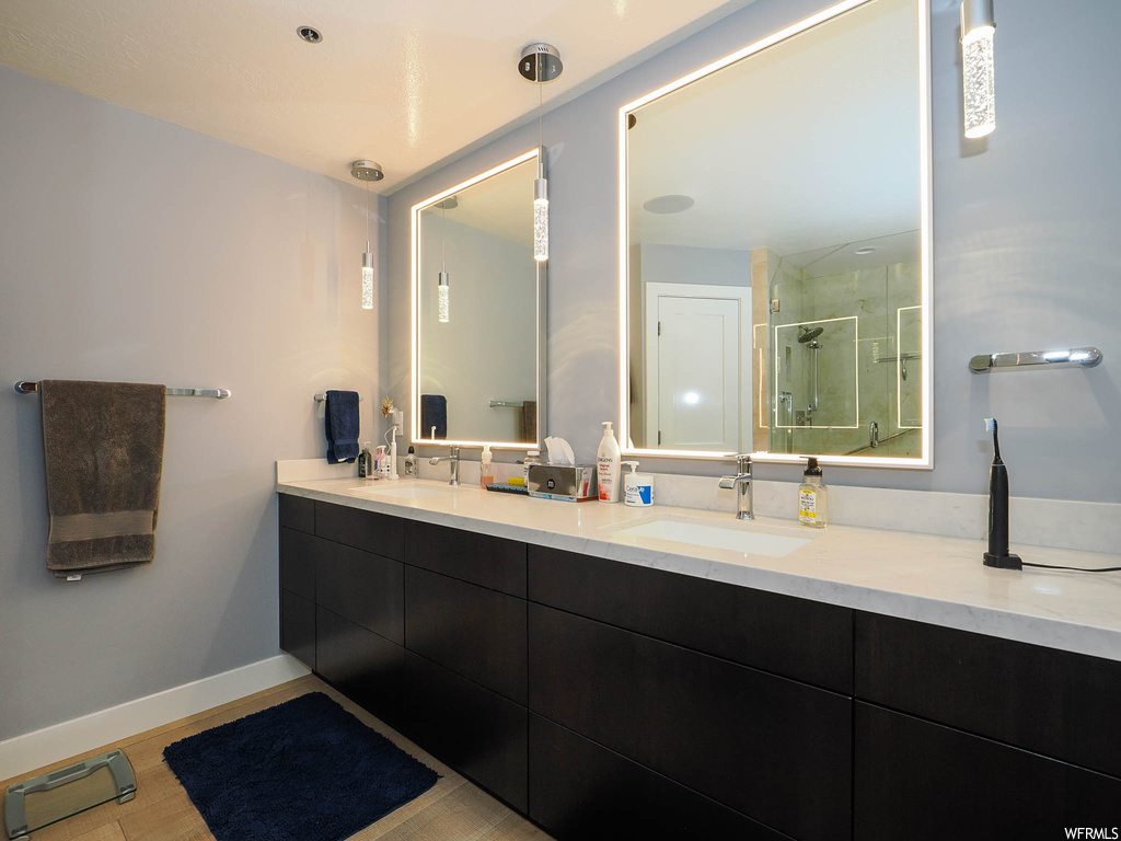 Bathroom with dual bowl vanity, hardwood / wood-style floors, and a tile shower