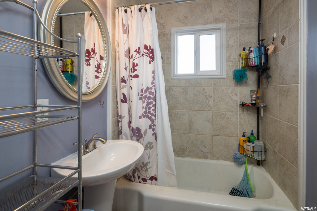 Bathroom featuring shower / bathtub combination with curtain and sink