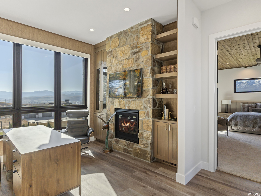 Living room with built in features, dark wood-type flooring, a stone fireplace, and a mountain view