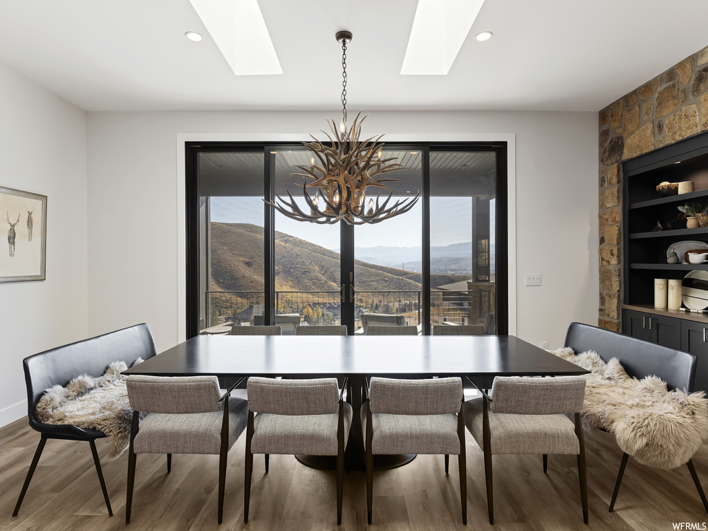 Dining space featuring a notable chandelier, a skylight, hardwood / wood-style flooring, and a mountain view