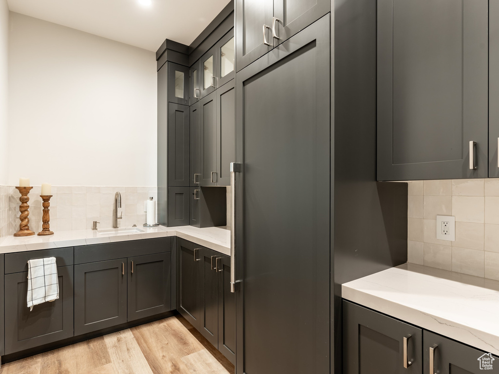 Kitchen featuring sink, light stone countertops, light hardwood / wood-style flooring, and backsplash