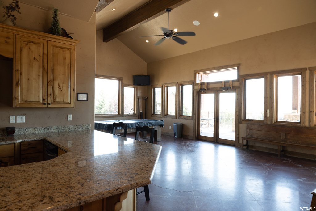 Kitchen featuring beamed ceiling, high vaulted ceiling, dark tile floors, light stone countertops, and ceiling fan
