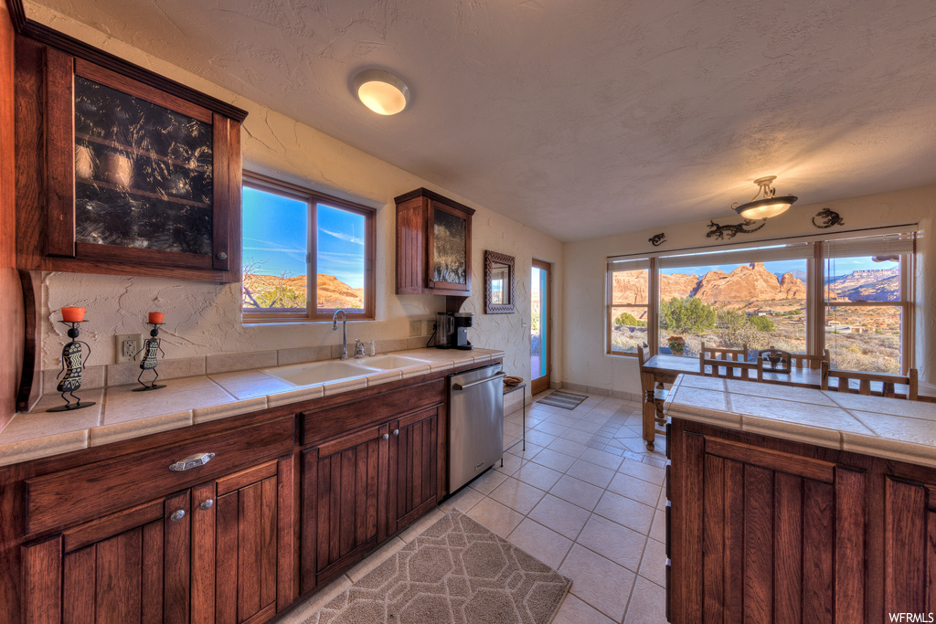 Kitchen featuring dishwasher, sink, tile countertops, a mountain view, and light tile floors