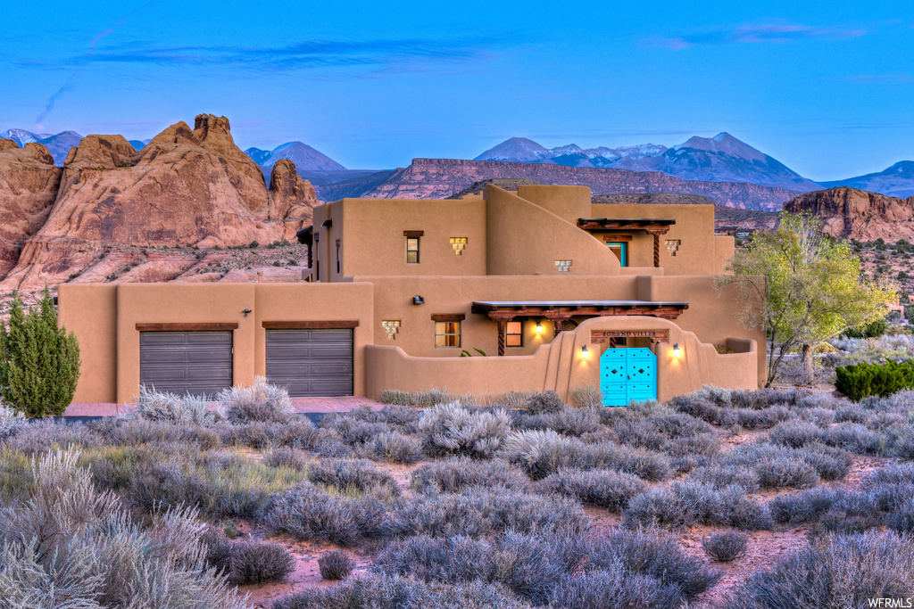 Pueblo-style home with a garage and a mountain view