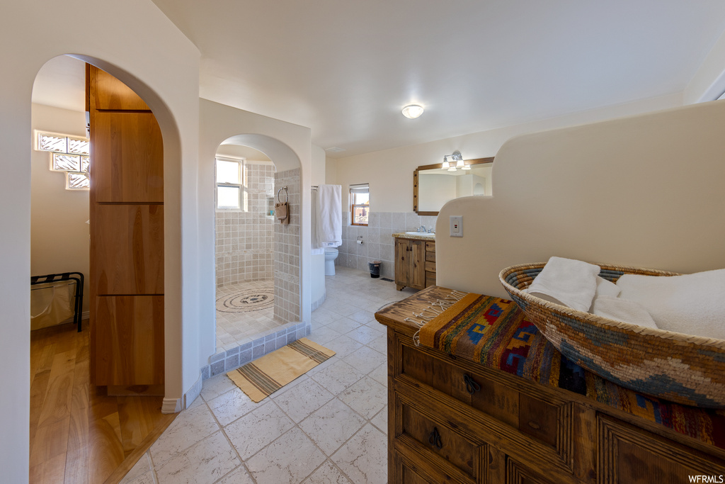 Interior space with tile walls, tiled shower, hardwood / wood-style flooring, and vanity