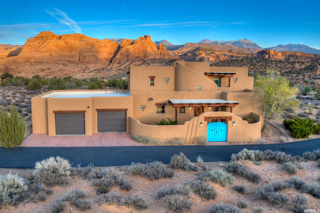 Pueblo-style home featuring a garage and a mountain view