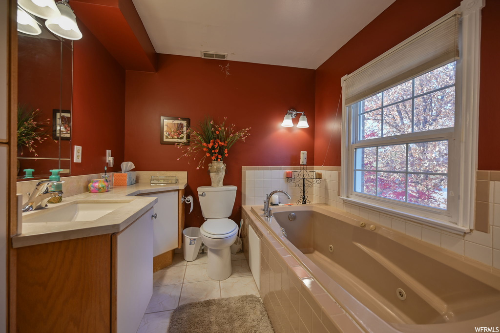Bathroom with tiled bath, tile flooring, oversized vanity, and toilet