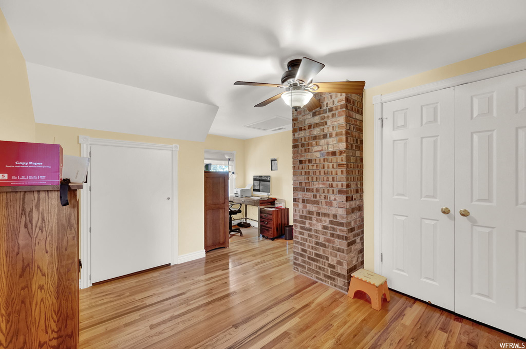 Interior space with ceiling fan, light wood-type flooring, brick wall, and a closet