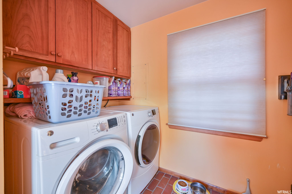 Washroom featuring independent washer and dryer, dark tile flooring, and cabinets