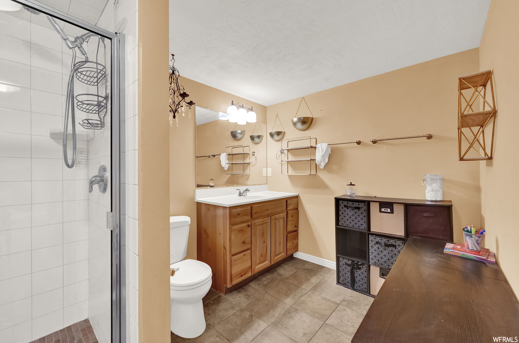 Bathroom with vanity, toilet, a shower with door, and tile flooring