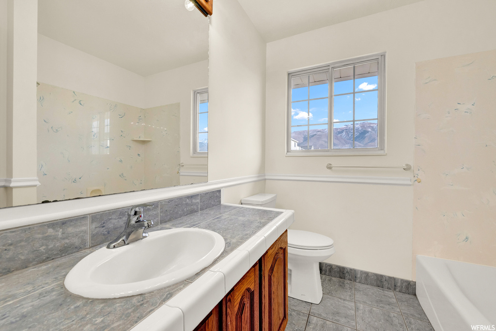 Full bathroom featuring toilet, tile flooring, bathing tub / shower combination, and vanity with extensive cabinet space