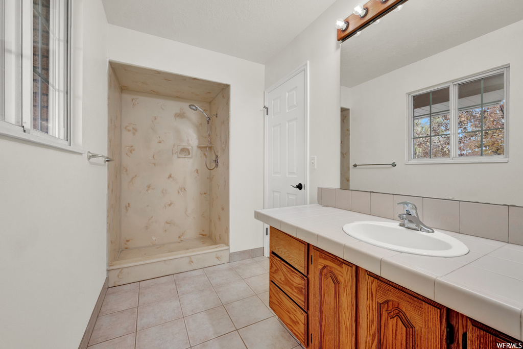 Bathroom with vanity, tile flooring, and a tile shower