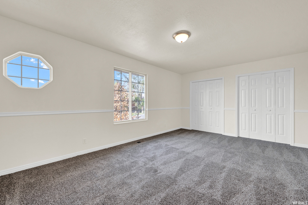 Unfurnished bedroom with dark carpet and two closets