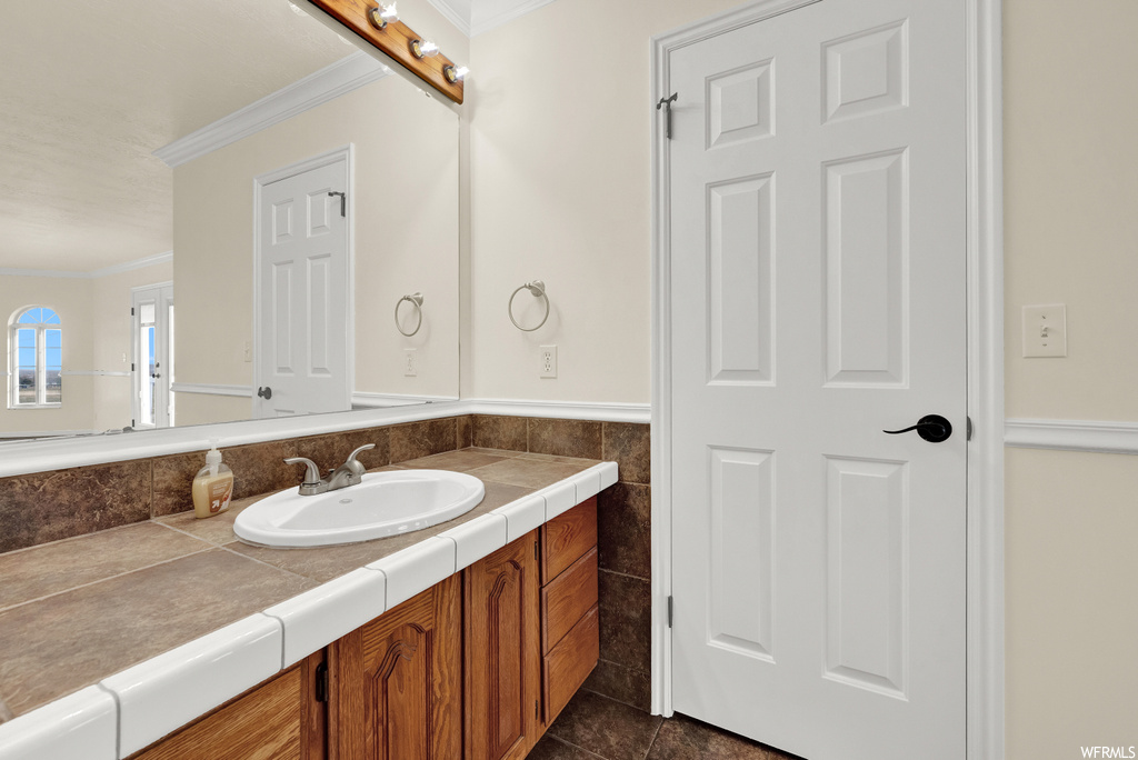 Bathroom featuring ornamental molding, tile flooring, and vanity
