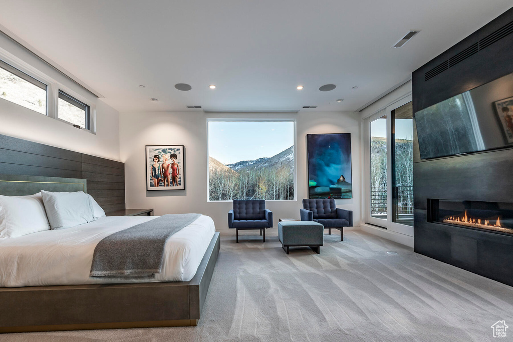 Bedroom featuring light colored carpet, access to exterior, and a mountain view