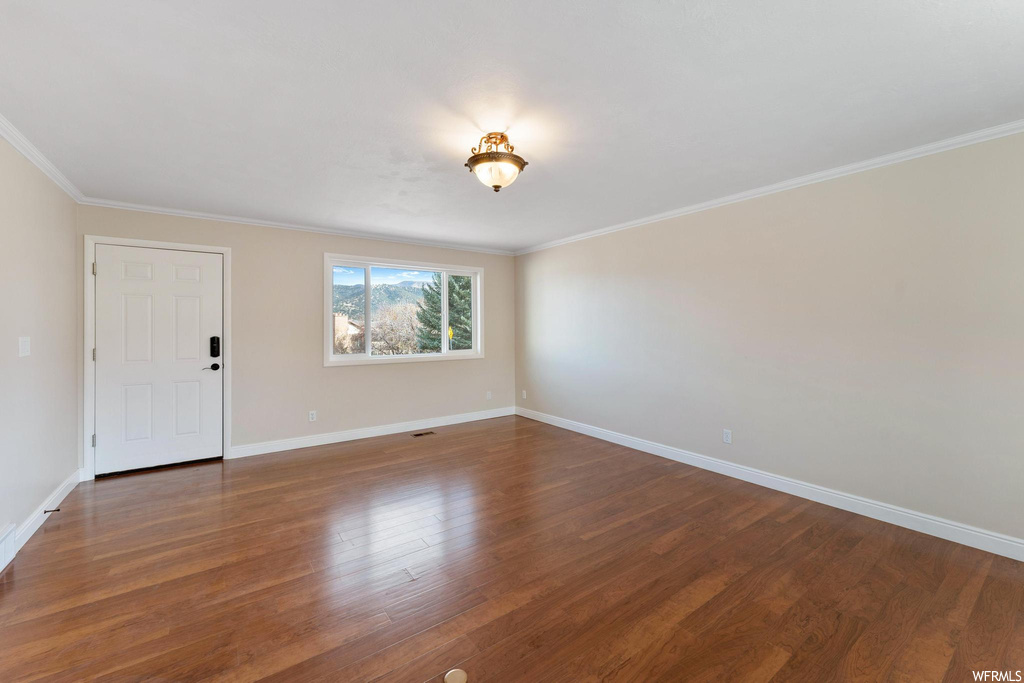 Unfurnished room with dark hardwood / wood-style floors and crown molding