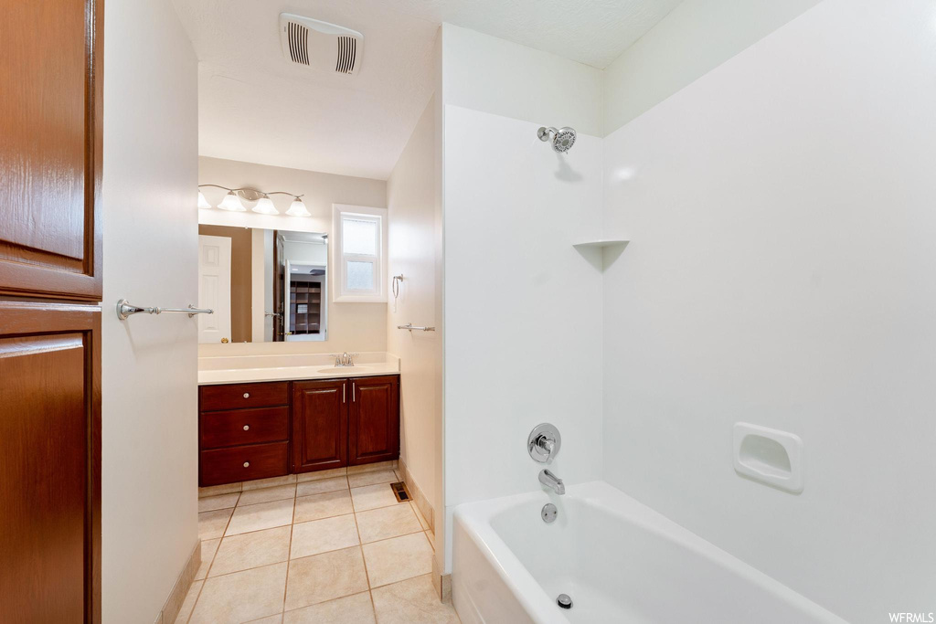 Bathroom with tub / shower combination, vanity, and tile floors