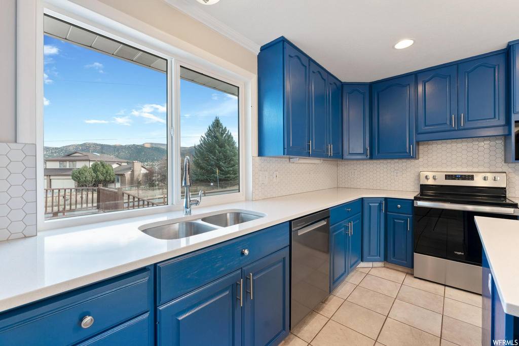 Kitchen with tasteful backsplash, sink, appliances with stainless steel finishes, and blue cabinetry