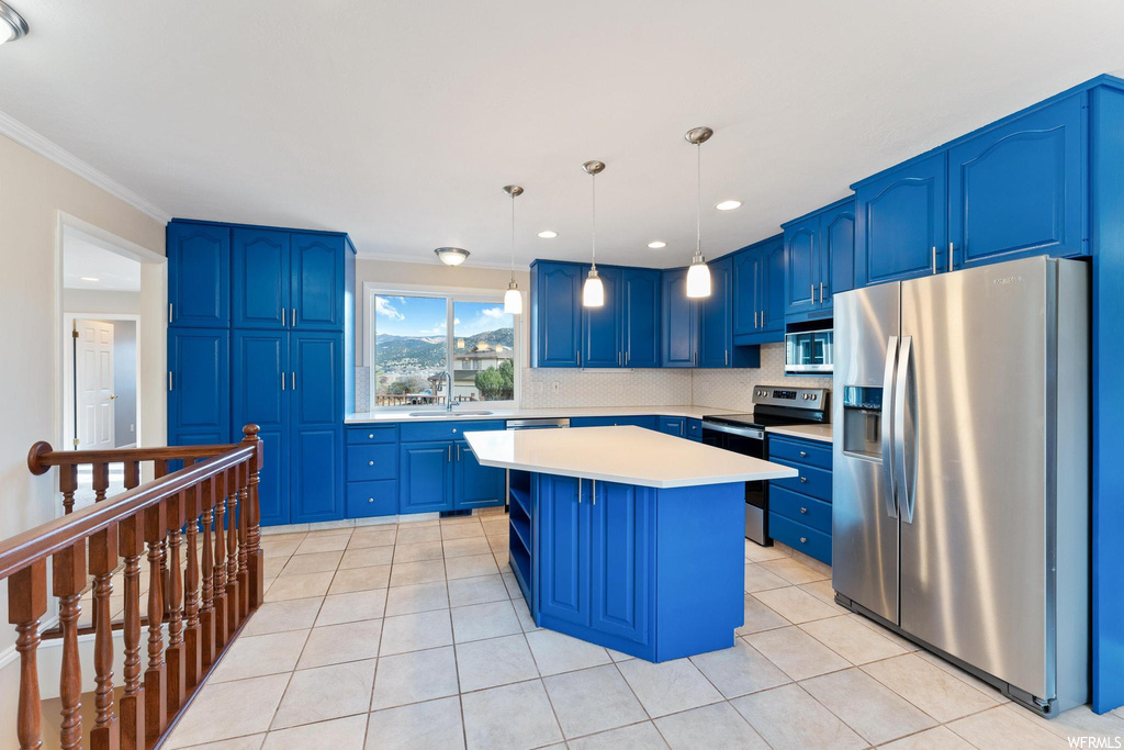 Kitchen with blue cabinetry, hanging light fixtures, and appliances with stainless steel finishes