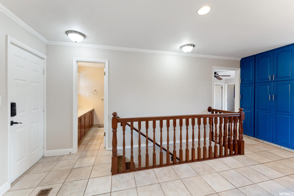 Hall featuring light tile flooring and crown molding