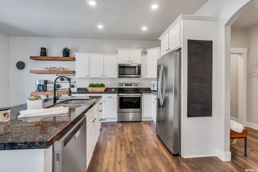 Kitchen featuring dark hardwood / wood-style floors, appliances with stainless steel finishes, and white cabinetry