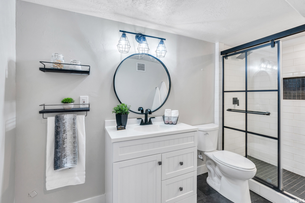 Bathroom featuring toilet, an enclosed shower, a textured ceiling, oversized vanity, and tile floors