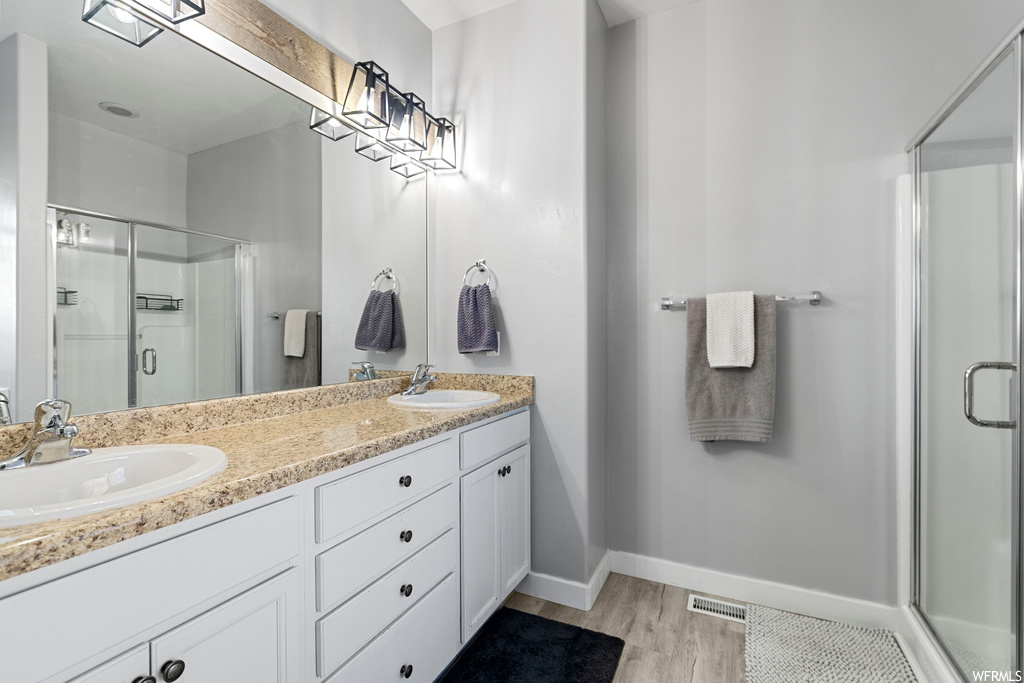 Bathroom featuring an enclosed shower, dual vanity, and hardwood / wood-style floors