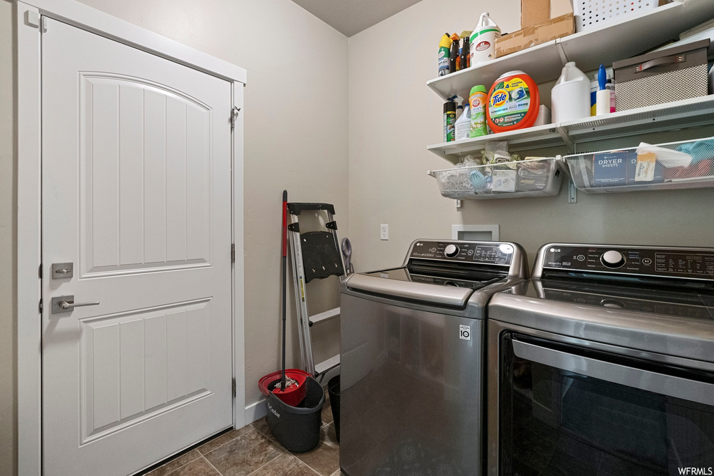 Clothes washing area with washing machine and clothes dryer and dark tile floors