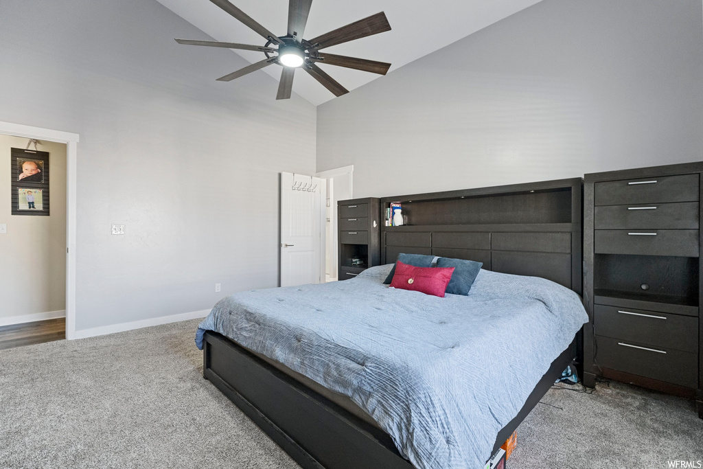 Carpeted bedroom featuring ceiling fan and high vaulted ceiling