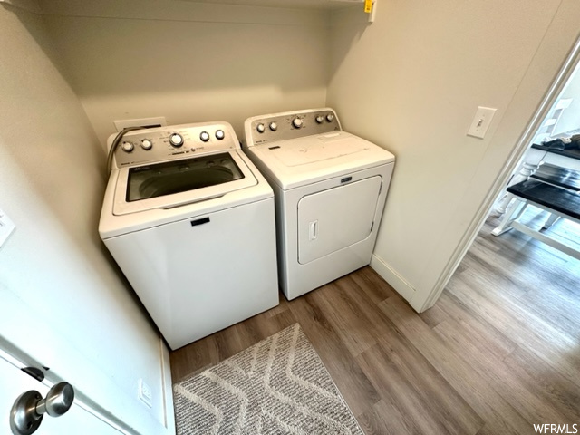 Laundry area with washing machine and clothes dryer and hardwood / wood-style flooring