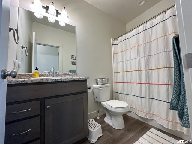 Bathroom with toilet, oversized vanity, and hardwood / wood-style floors