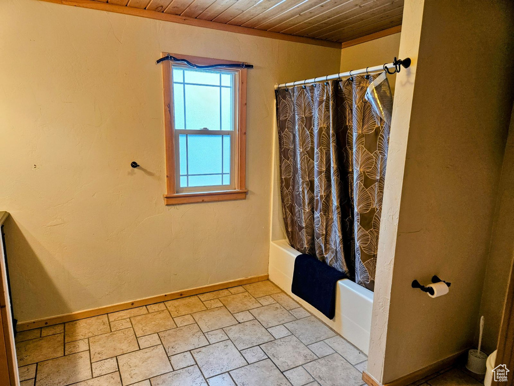 Bathroom with tile flooring, wood ceiling, and shower / bath combo with shower curtain