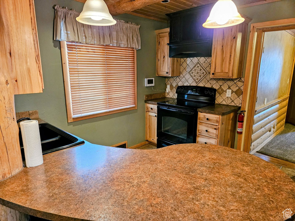 Kitchen with premium range hood, hanging light fixtures, backsplash, and black / electric stove