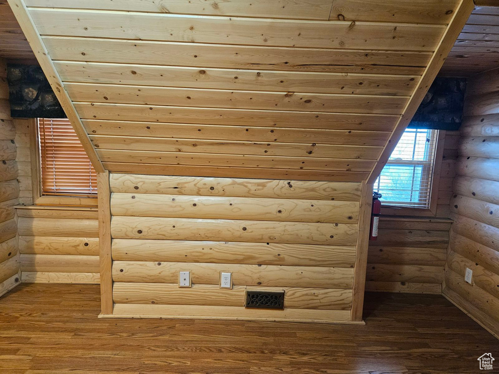 Additional living space with log walls, dark hardwood / wood-style flooring, and wood ceiling