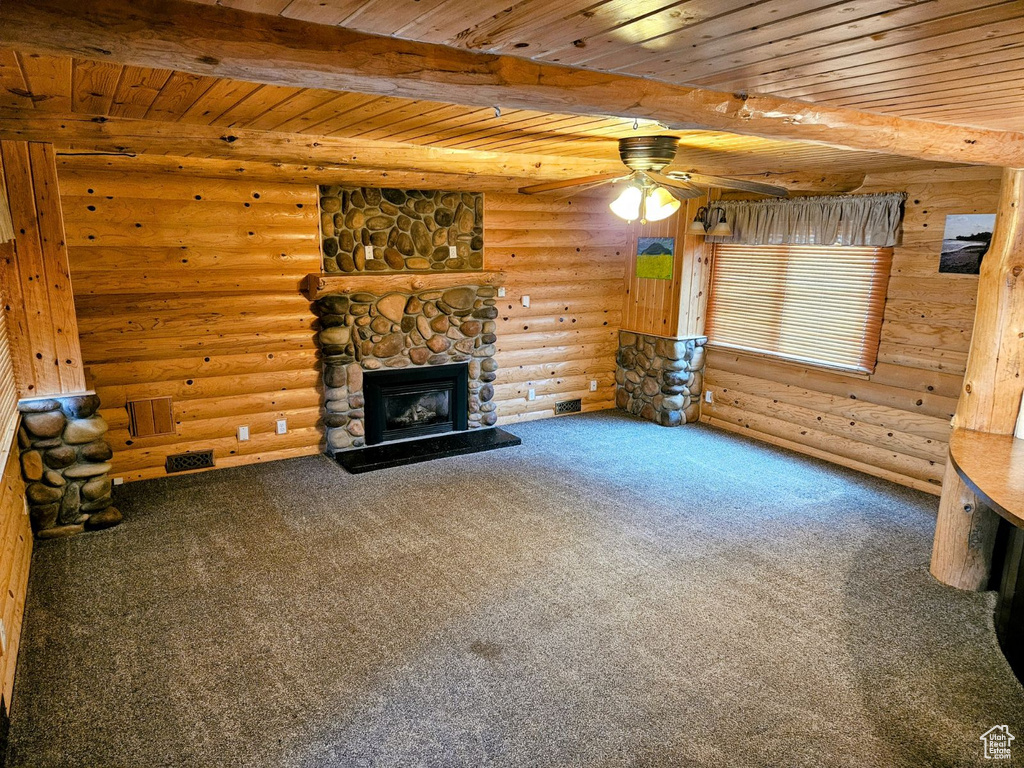 Unfurnished living room featuring ceiling fan, carpet, wood ceiling, a fireplace, and rustic walls