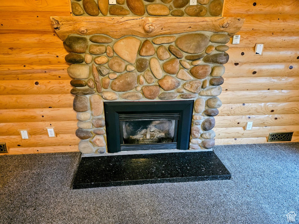 Interior details with carpet flooring, rustic walls, and a fireplace