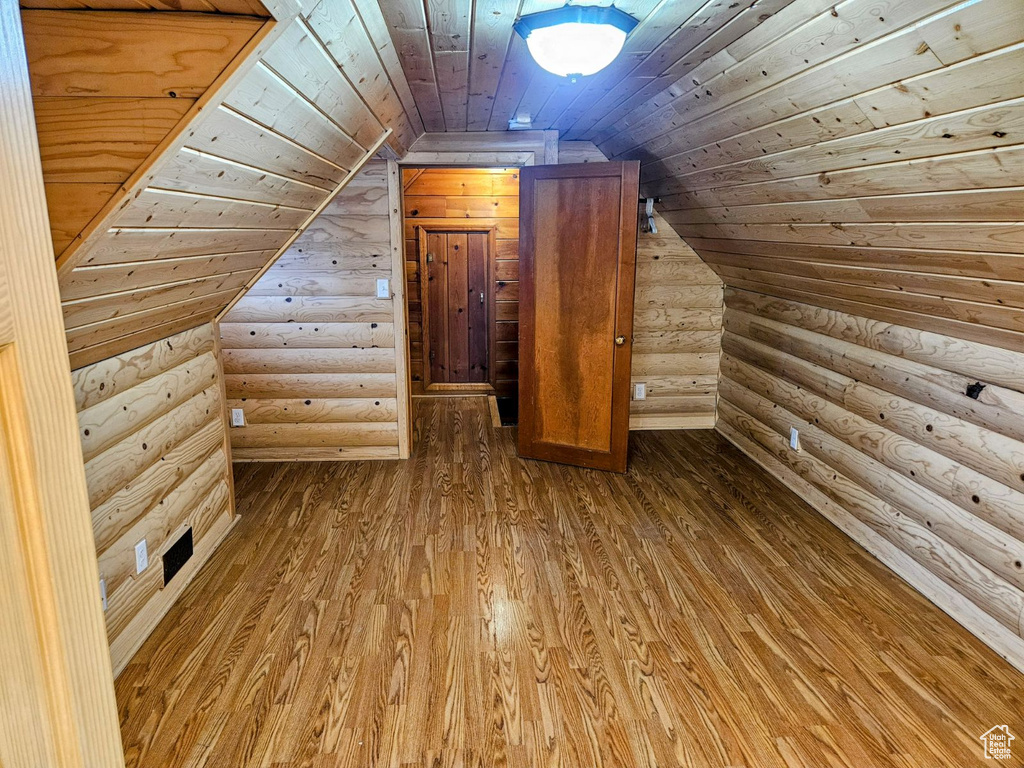 Bonus room featuring lofted ceiling, log walls, wood ceiling, and light hardwood / wood-style floors