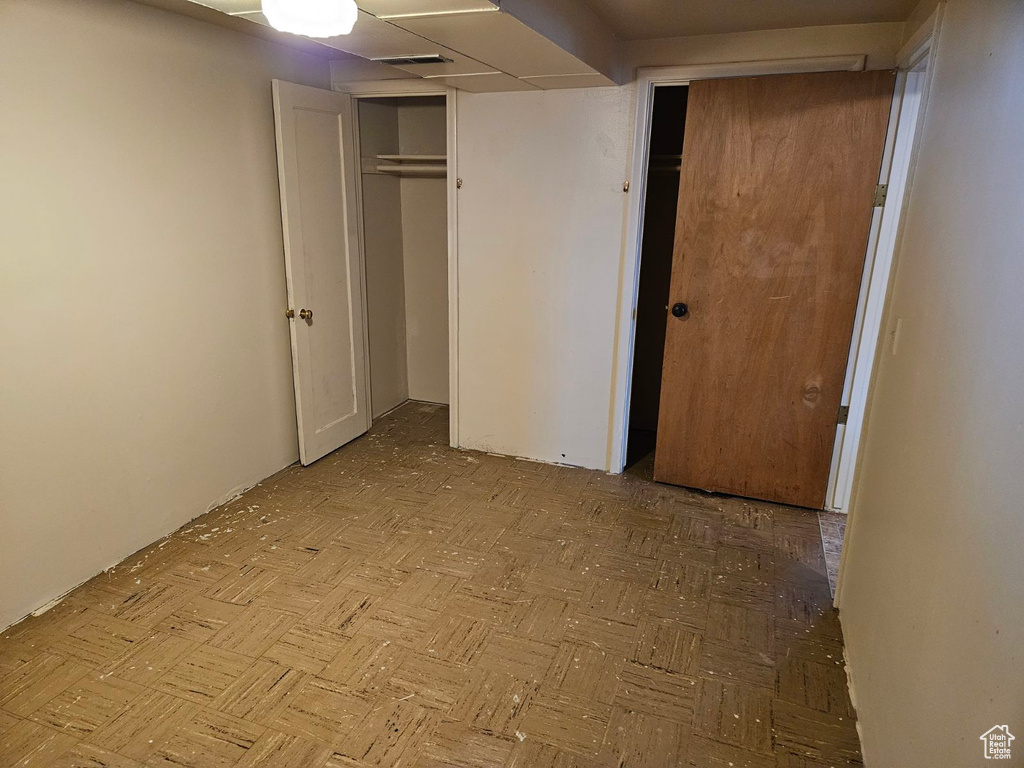 Unfurnished bedroom featuring a closet and light parquet floors