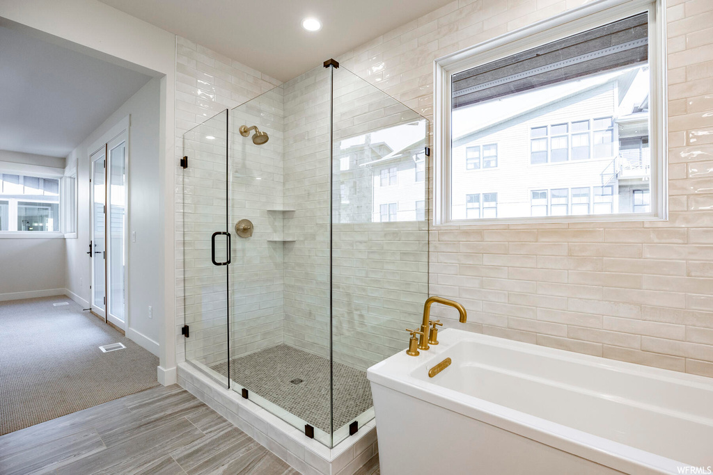 Bathroom with shower with separate bathtub, tile floors, and a healthy amount of sunlight