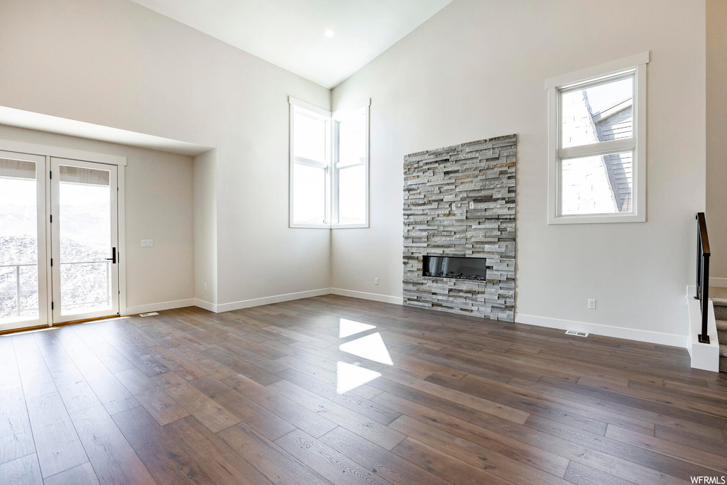 Unfurnished living room featuring a fireplace, a healthy amount of sunlight, and dark hardwood / wood-style flooring