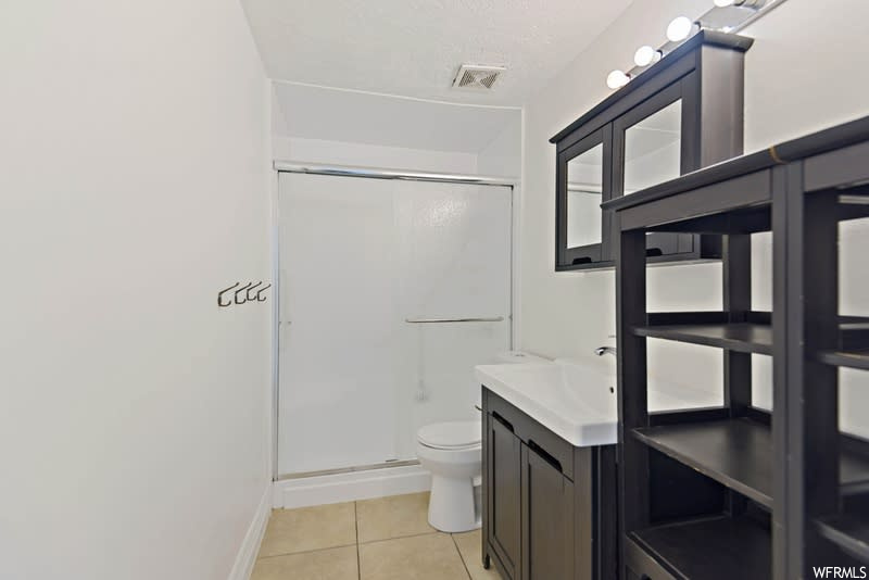 Bathroom featuring walk in shower, toilet, oversized vanity, and tile flooring